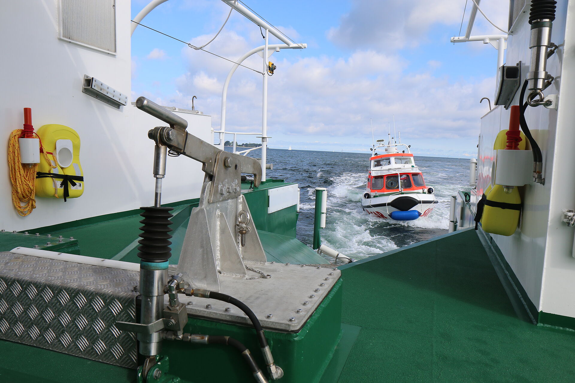 Blick vom Seenotrettungskreuzer BERLIN durch die geöffnete Heckklappe auf die Ostsee. Das Tochterboot STEPPKE manovriert bei langsamer Fahrt in die Heckwanne des Mutterschiffs.