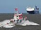 Seenotrettungskreuzer fährt auf großes Containerschiff zu