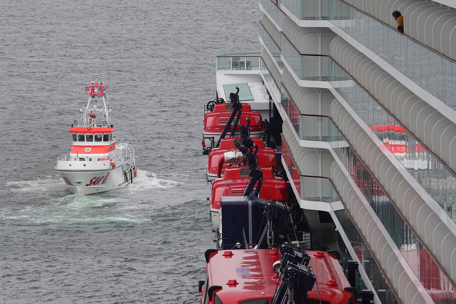 Ein Seenotrettungskreuzer nähert sich einem Kreuzfahrtschiff.