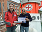 Rotarier (r.) überreicht symbolischen Spendenscheck des Rotary-Clubs Senden an DGzRS-Pressesprecher in der DGzRS-Zentrale Bremen an Bord des Museumskreuzers H.-J.-KRATSCHKE.