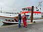 Spendenübergabe im Hafen vor dem Seenotrettungskreuzers PIDDER LÜNG. DGzRS-Vormann in roter Dienstkleidung (r.) schüttelt die Hand des Spenders.