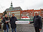 Immobilienmaklerin Sarah Schaper mit DGzRS-Sammelschiffchen in der Hand neben Niklas Niemeyer, Geschäftsführer des Engel & Völkers-Büros in Emden, der gemeinsam mit Wilhelm-Alfred Brüning von der DGzRS ein Schild #teamseenotretter hält. Im Hintergrund das Rathaus und Museumskreuzer GEORG BREUSING.