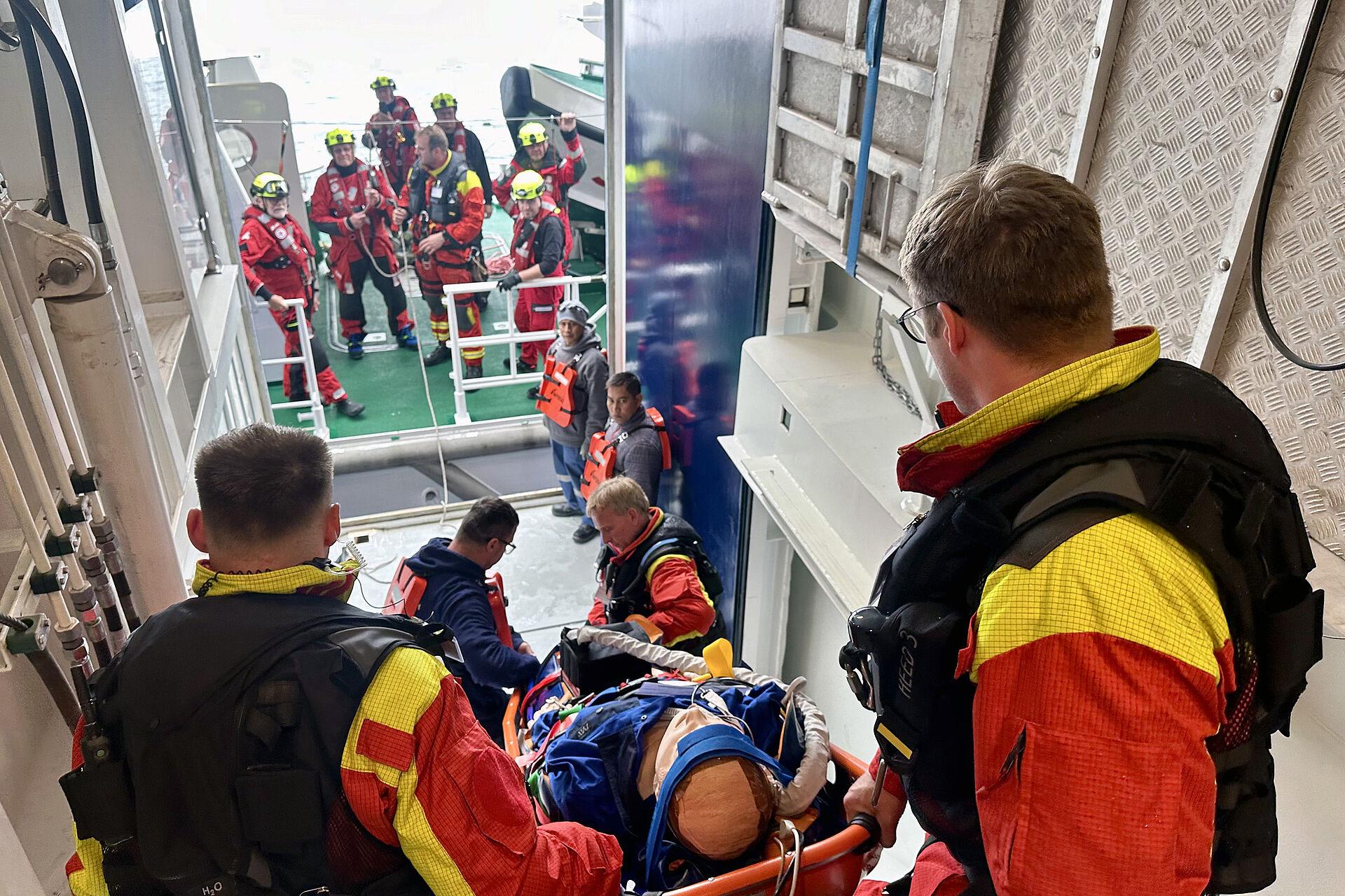 Rettungskräfte tragen eine Trage eine Treppe herunter, im Hintergrund sind weitere Rettungskräfte zu sehen